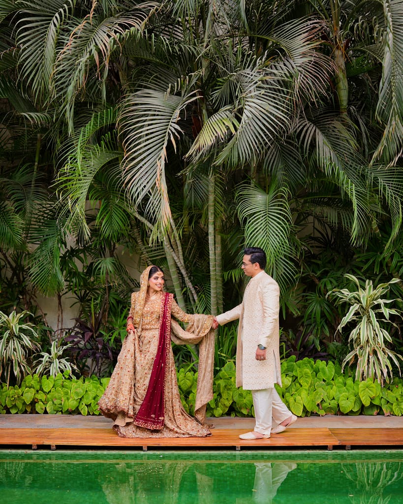 Best Photo Studio In Karachi photographing bride and groom walking together at a poolside garden wedding shoot